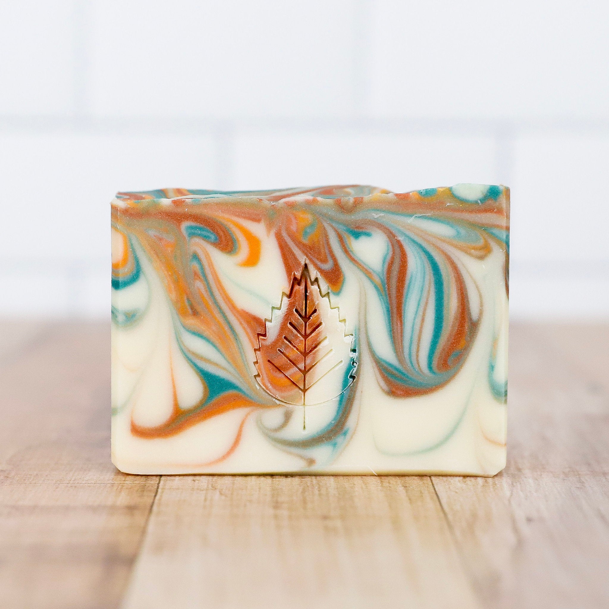 Marbled soap bar with a leaf cutout on a wooden surface