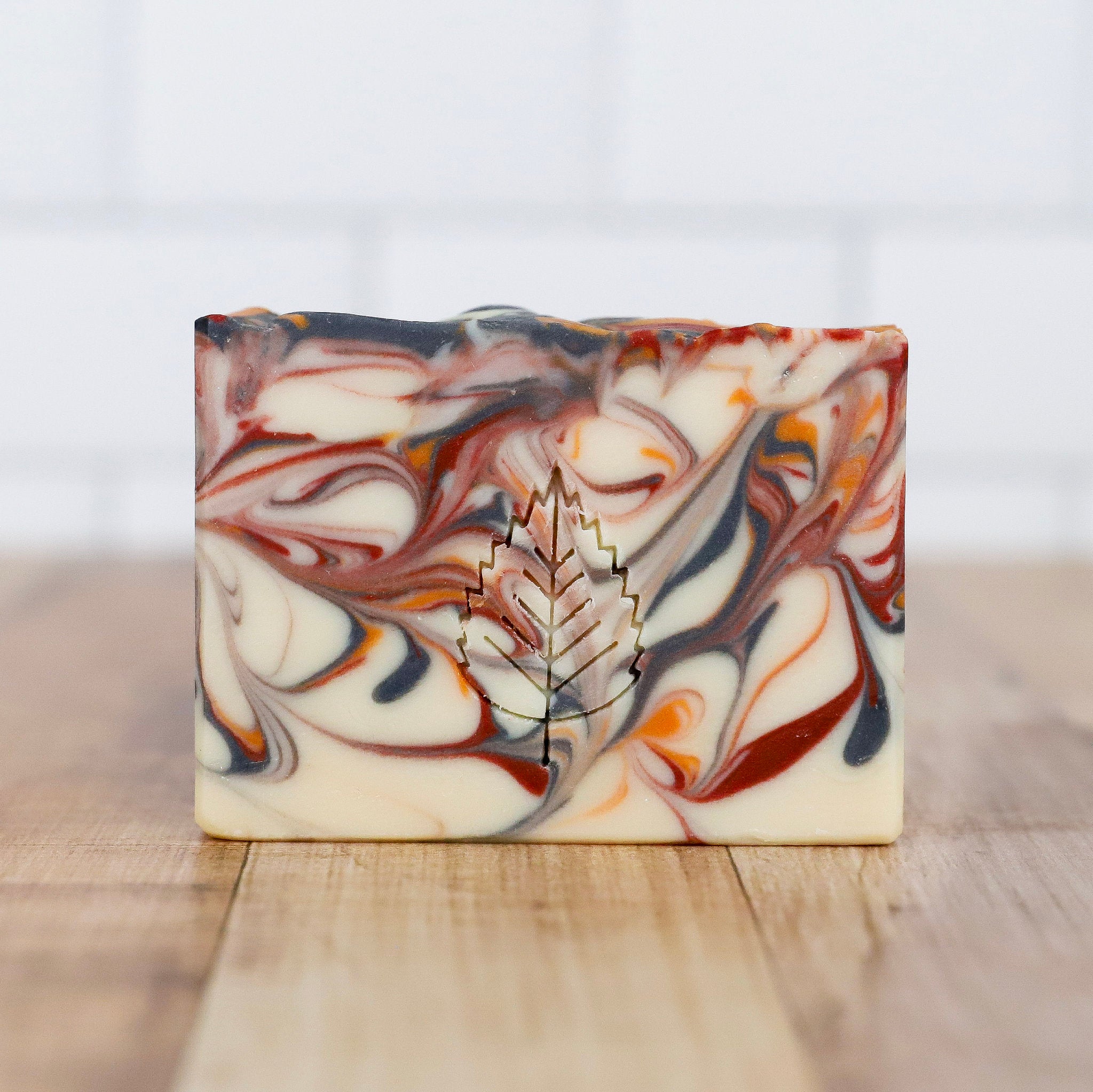 Marbled soap bar with a leaf design on a wooden surface
