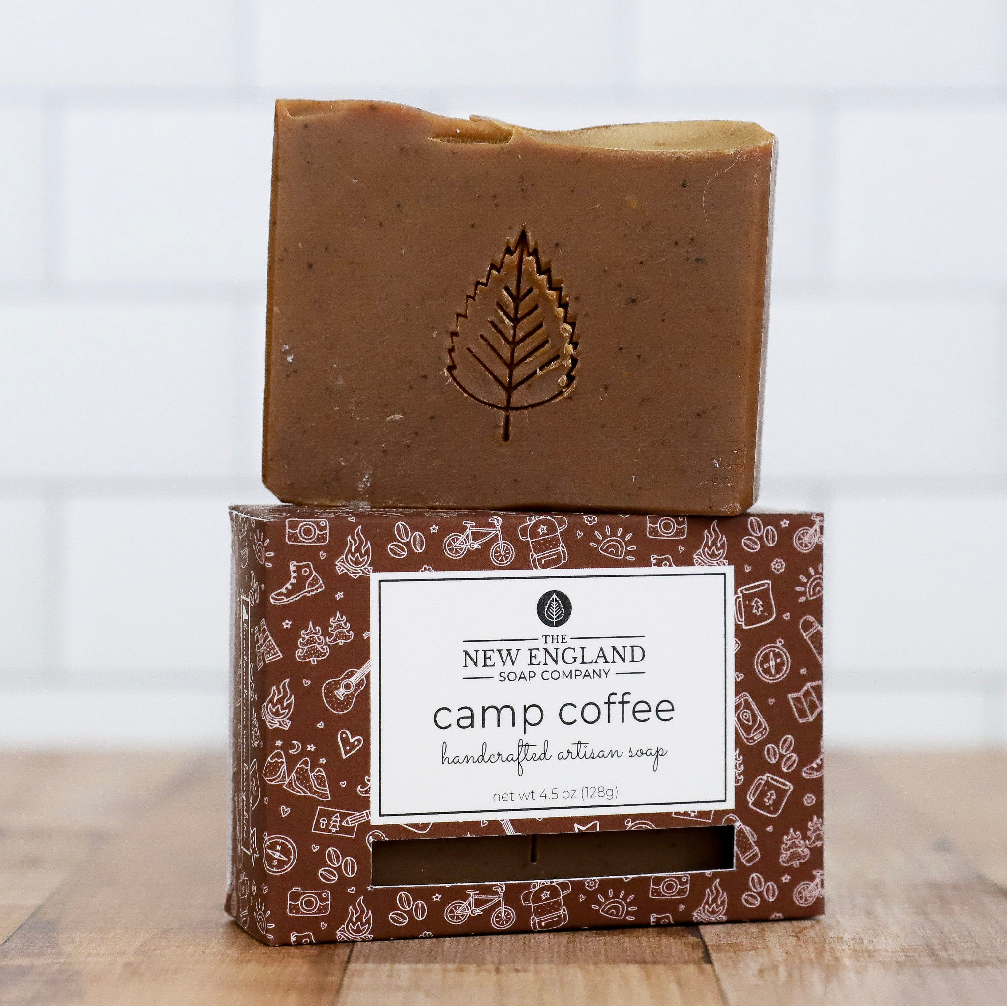 Bar of soap with a leaf impression on top of its packaging, featuring the New England Soap Company branding.