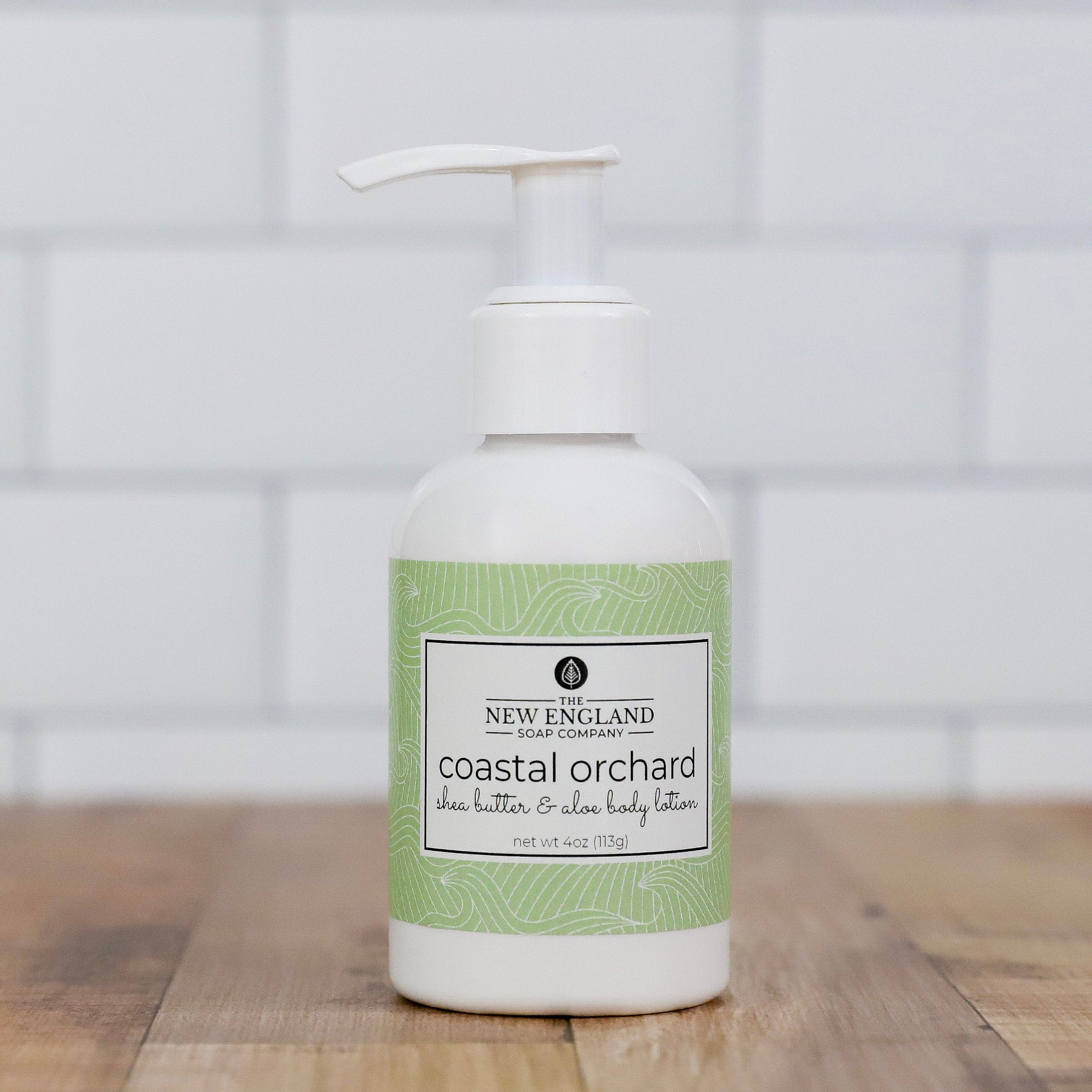 Body lotion bottle with green label on a wooden surface Coastal Orchard Hand and Body Lotion 4 oz