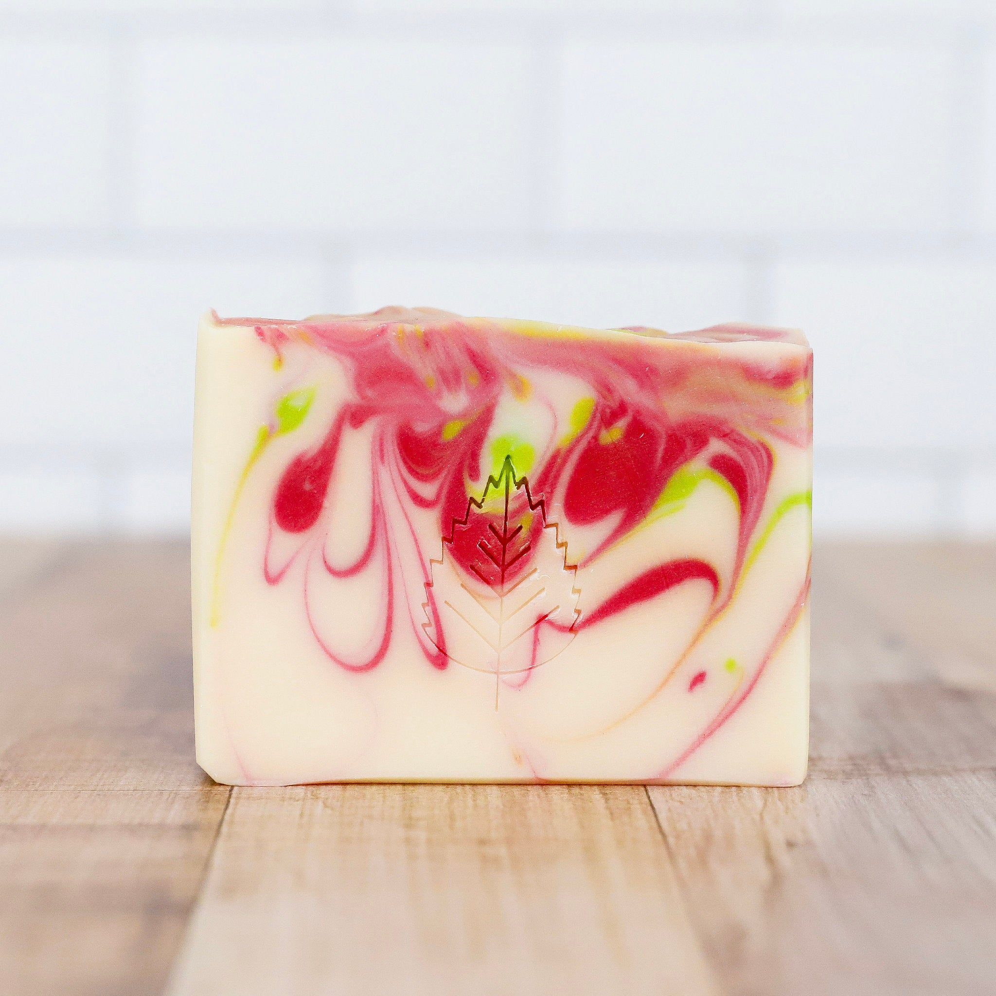 Swirled soap bar with pink and green on a wooden surface