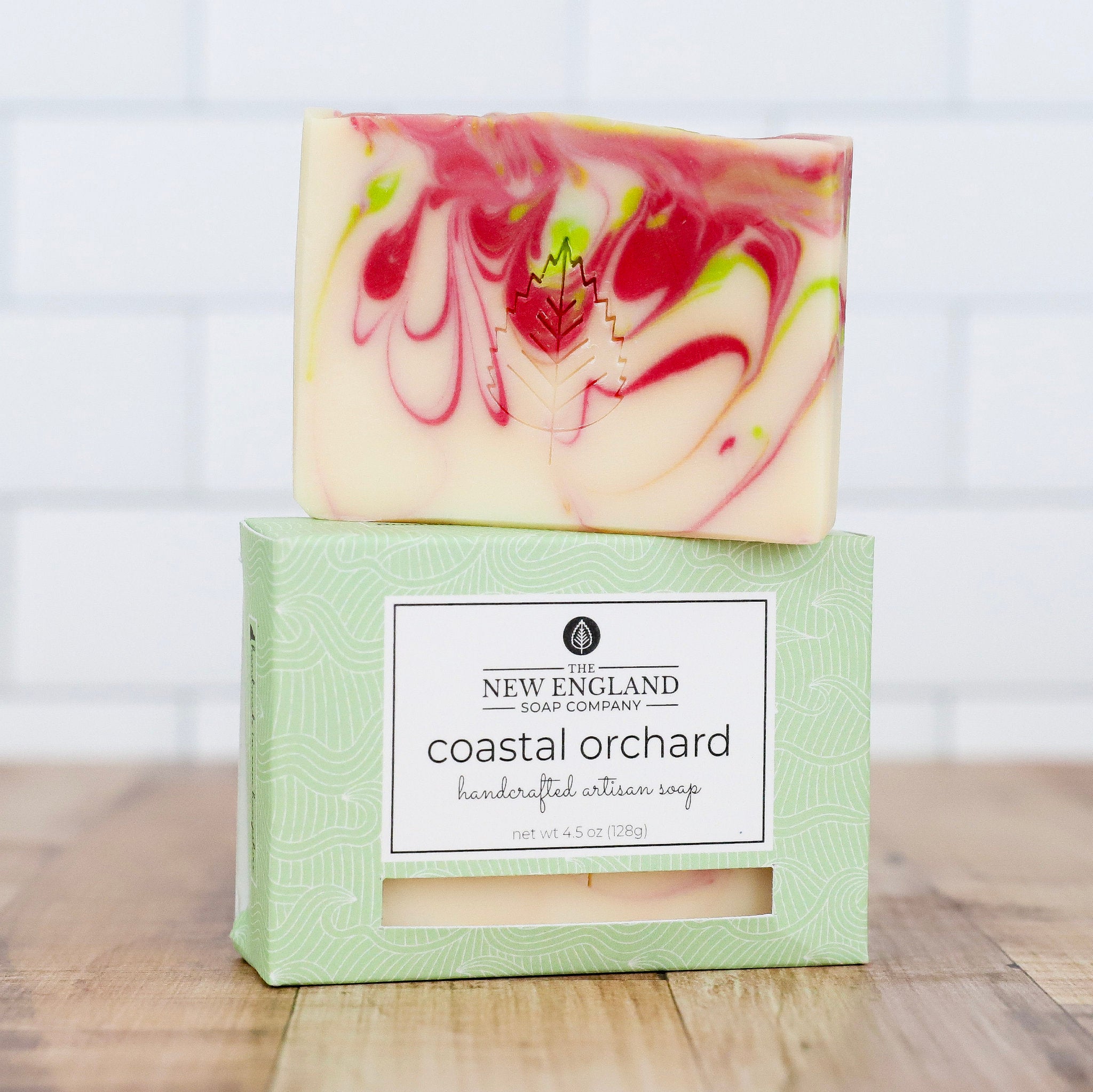 Handcrafted artisan soap with a marbled design on top of its packaging, featuring the New England Soap Company branding.