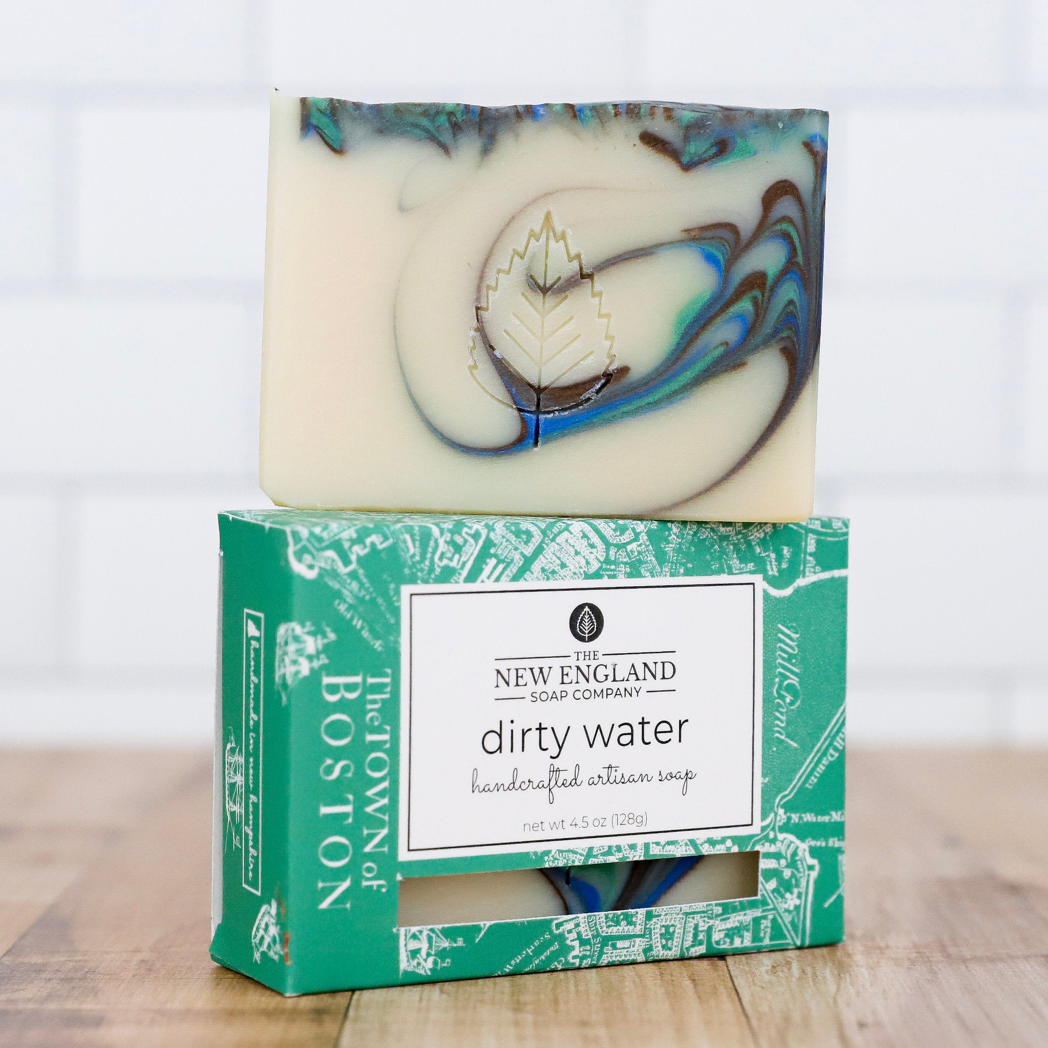 Handcrafted artisian soap with marbled design on a branded box, set against a neutral background.