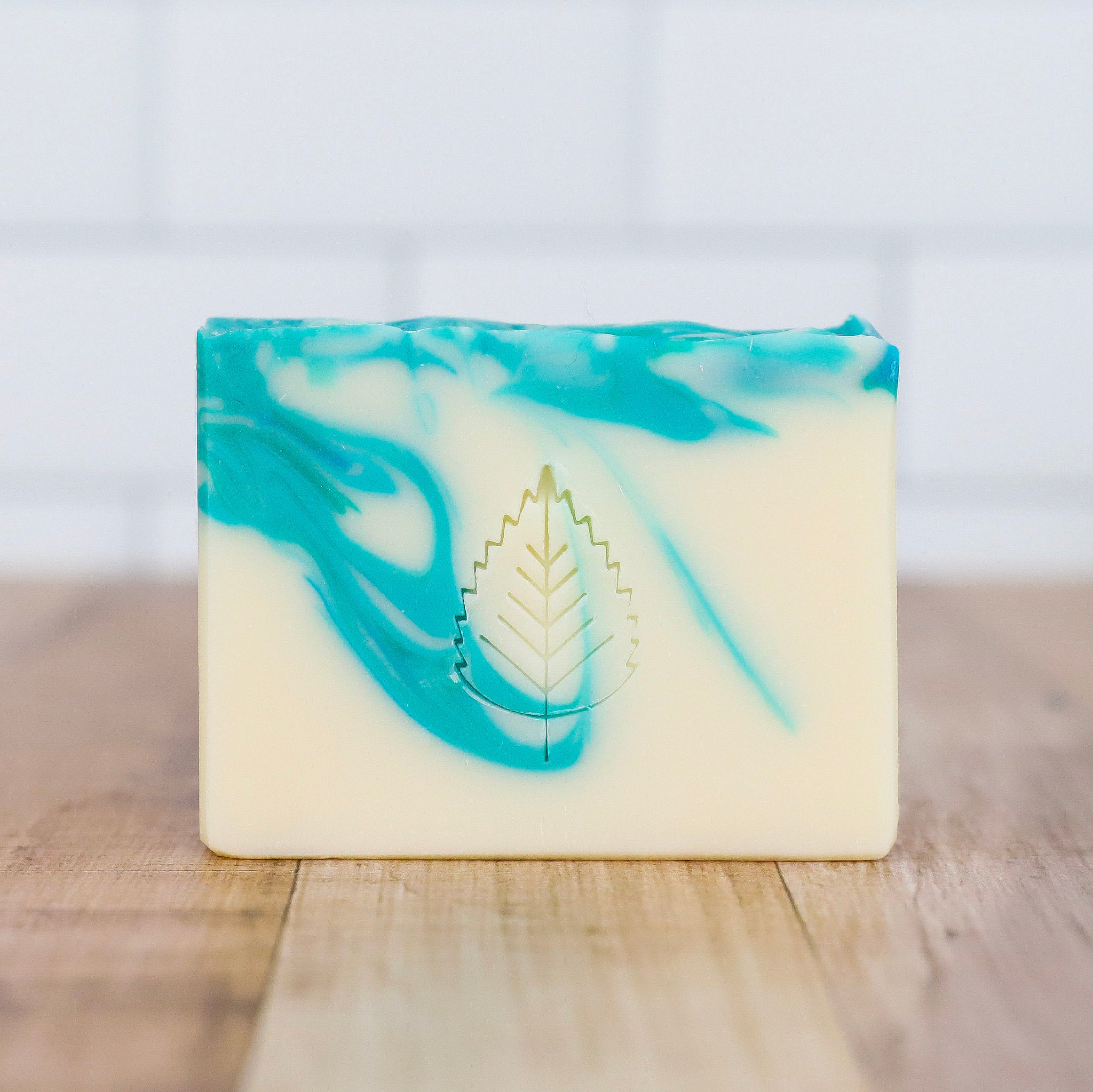 Bar of soap with blue and green swirls on a wooden surface