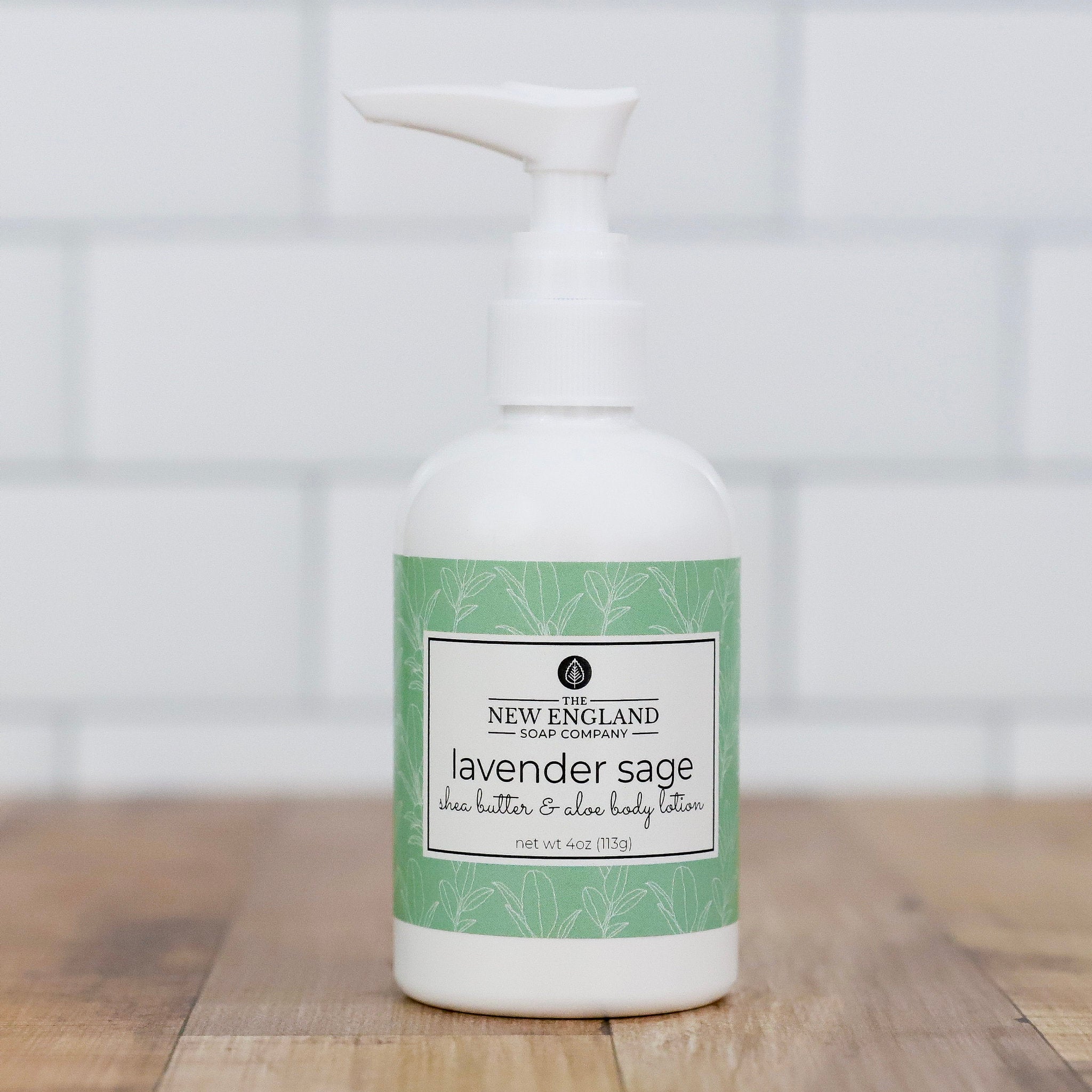 Lavender sage body lotion bottle with a white pump on a wooden surface and light background Lavender Sage Hand and Body Lotion 4 oz