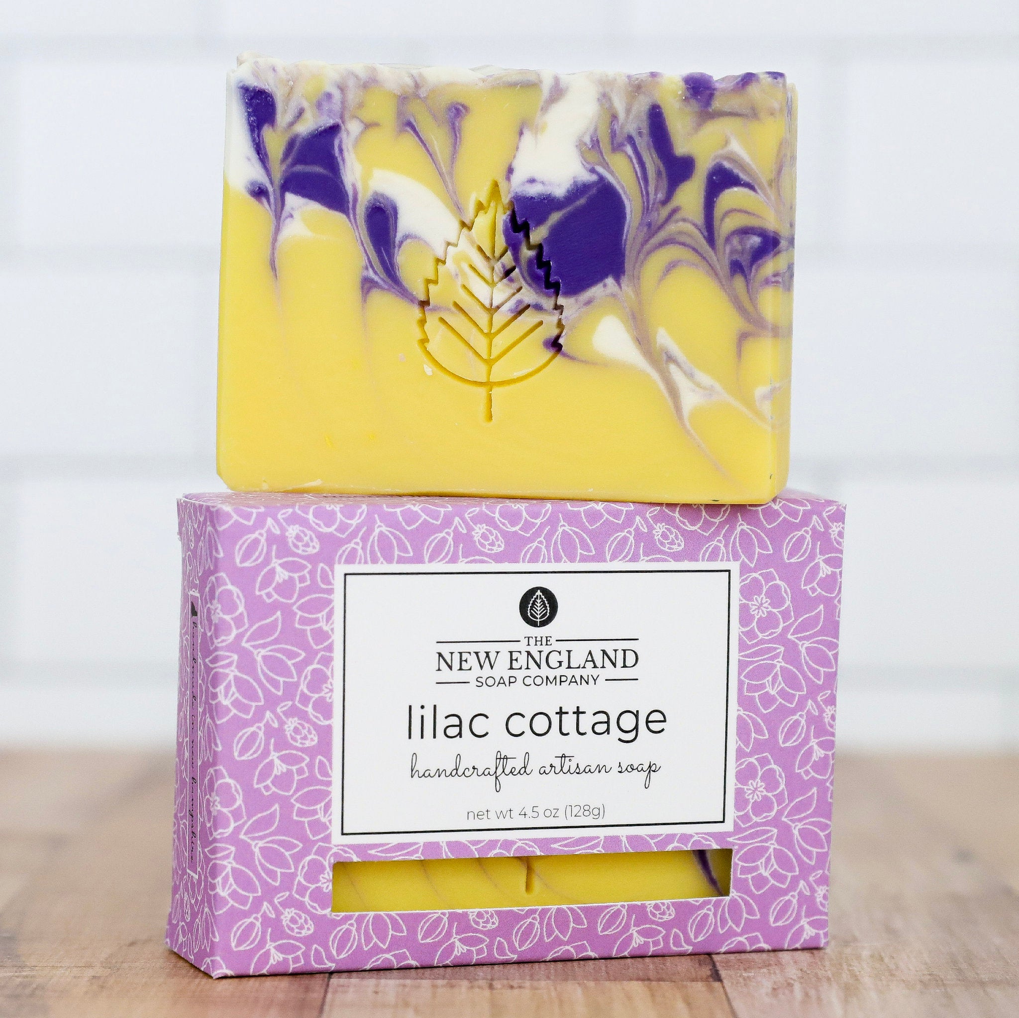 Handcrafted artisan soap with marbled design and packaging from New England Soap Company on a light background