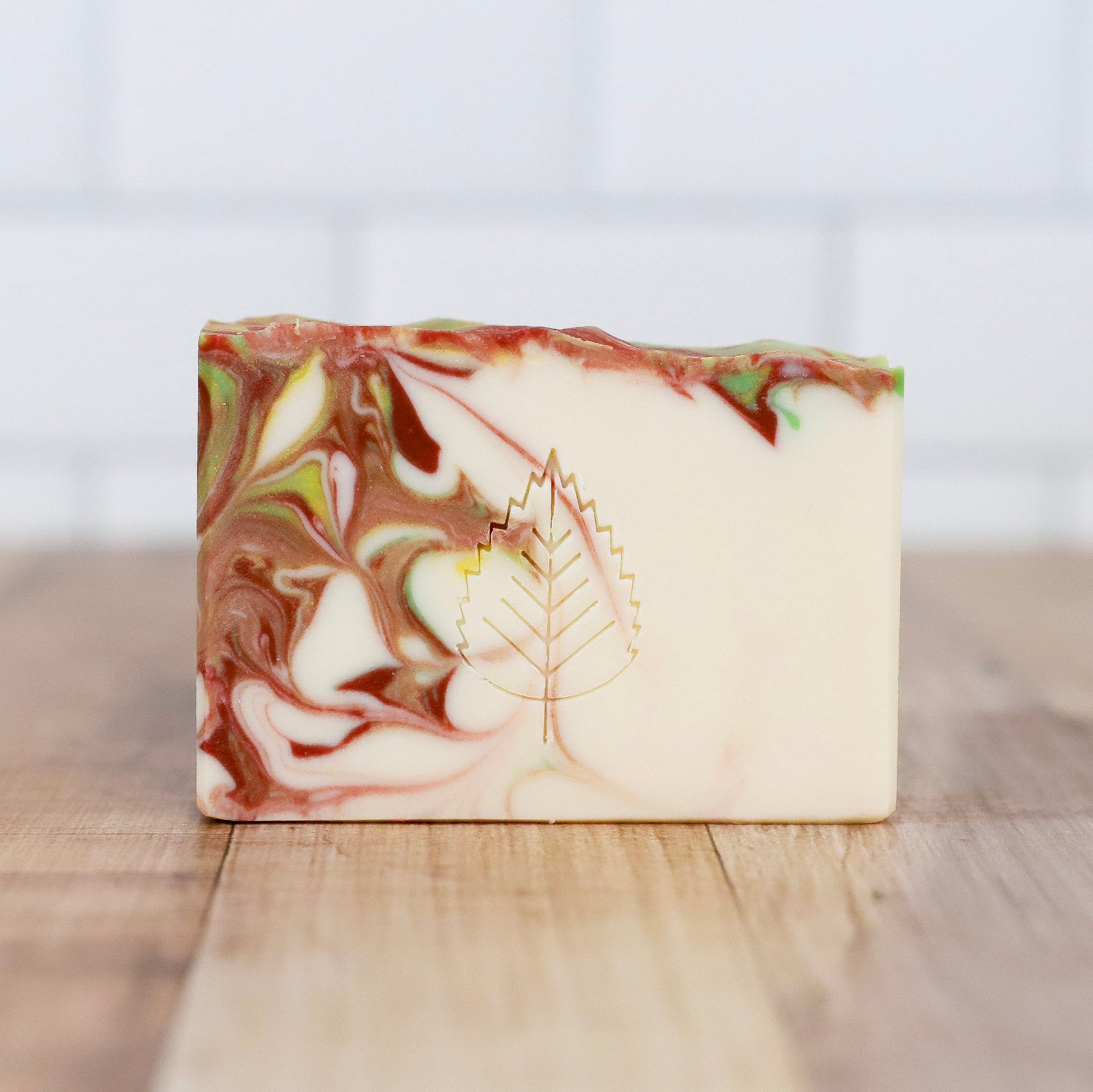 Marbled soap bar with a leaf design on a wooden surface