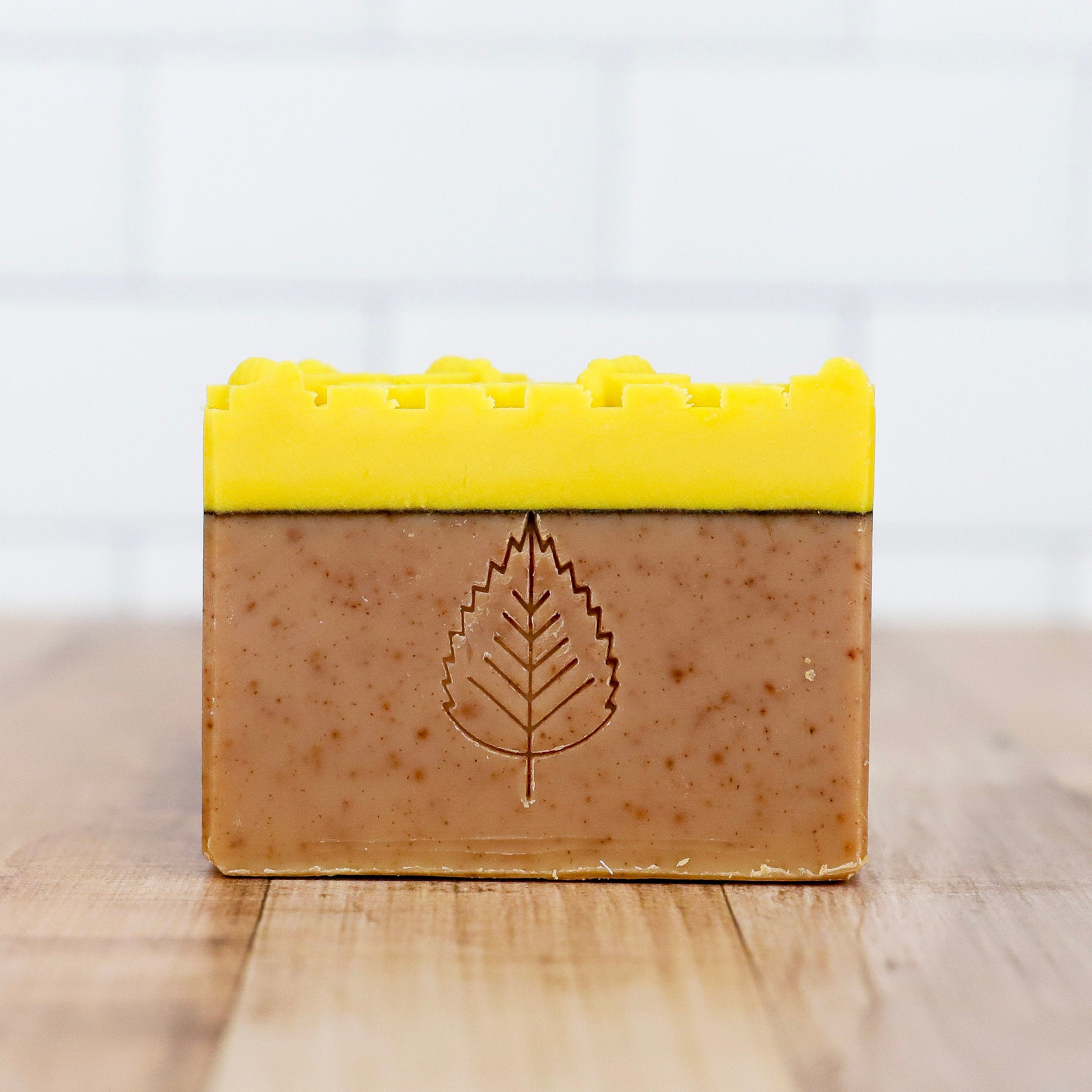 Bar of soap with a yellow top and leaf design on a light background