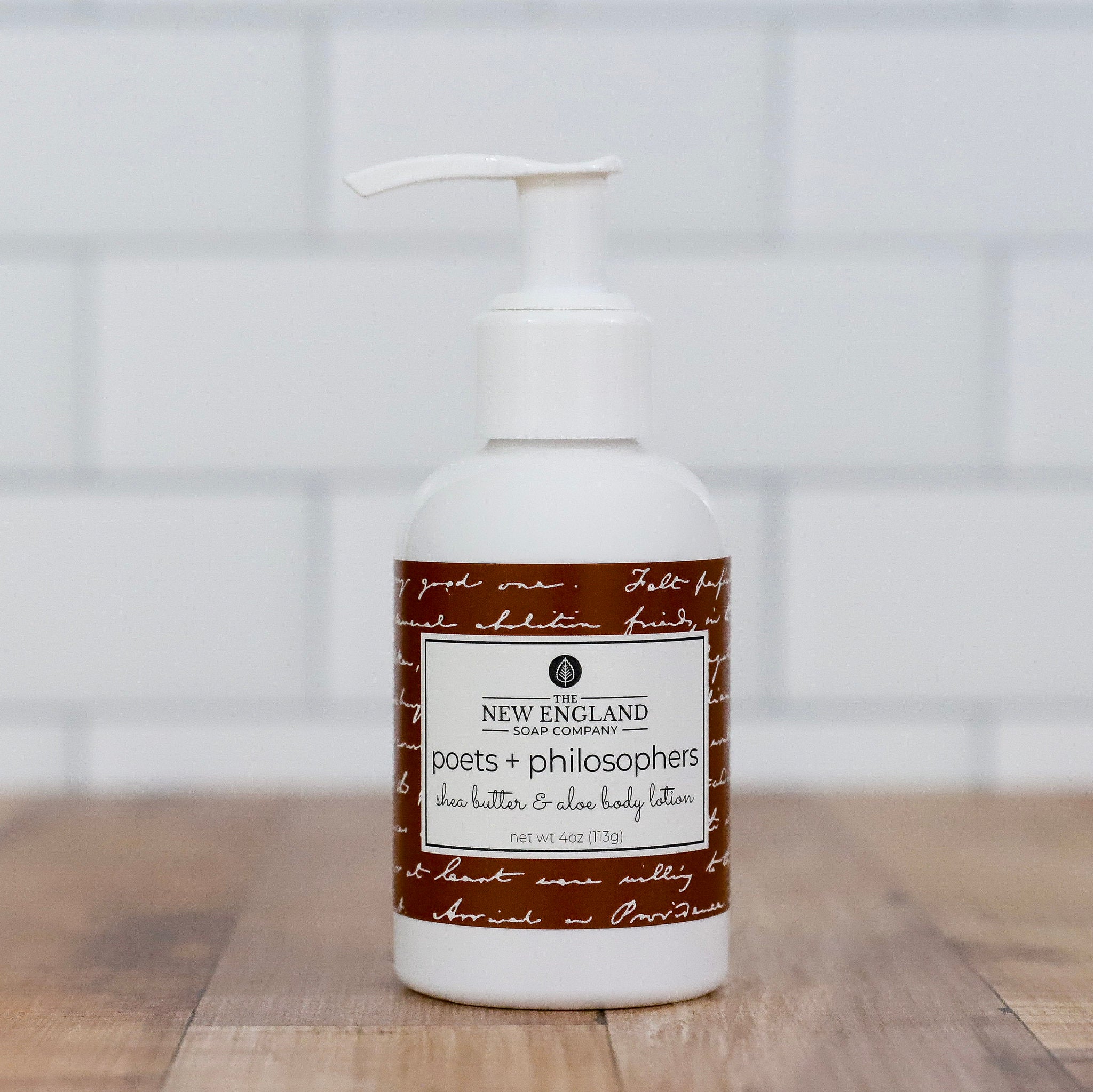 Body lotion bottle with a label on a wooden surface and white background Poets and Philosophers Hand and Body Lotion 4 oz
