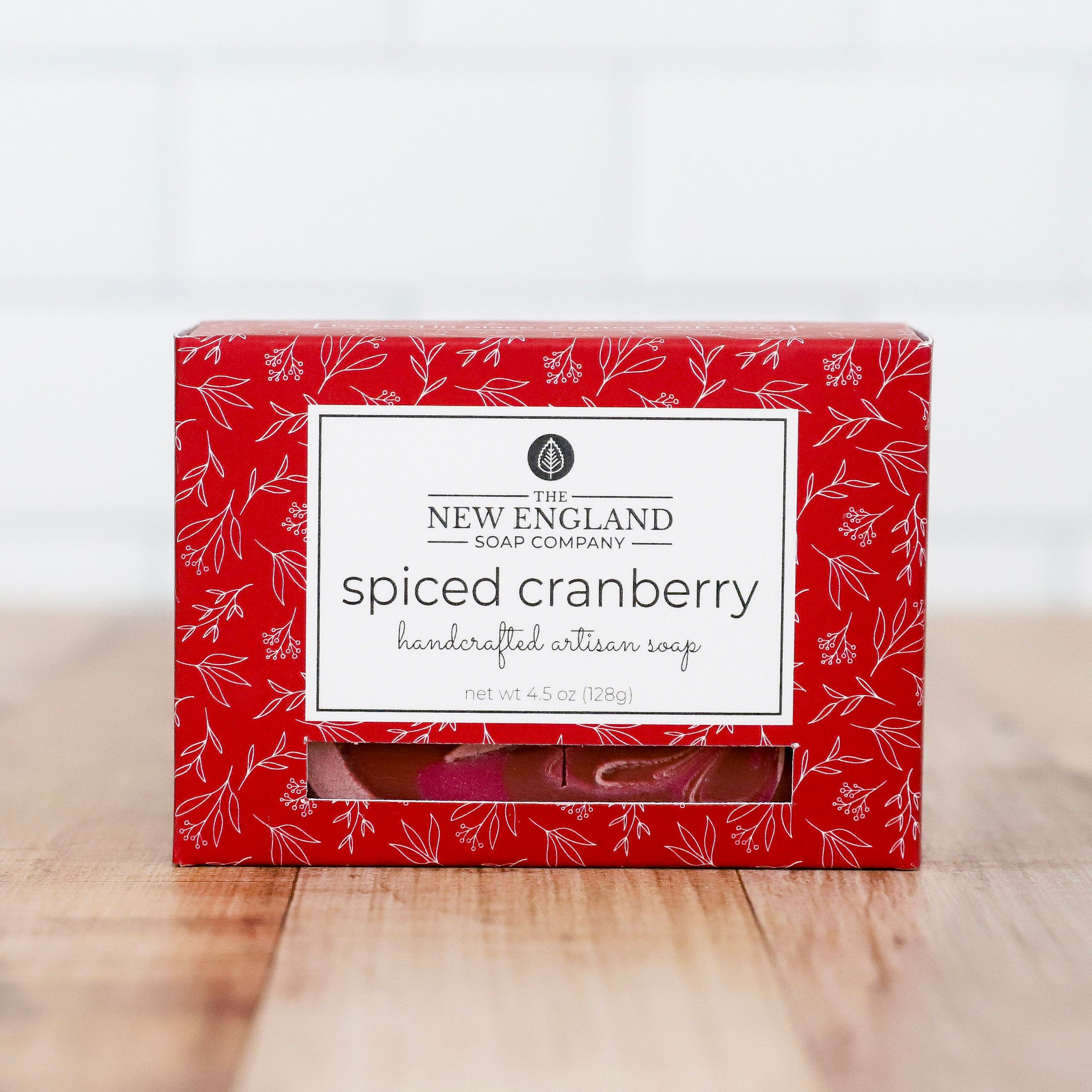Red box of New England Soap Company spiced cranberry soap on a wooden surface with a white background