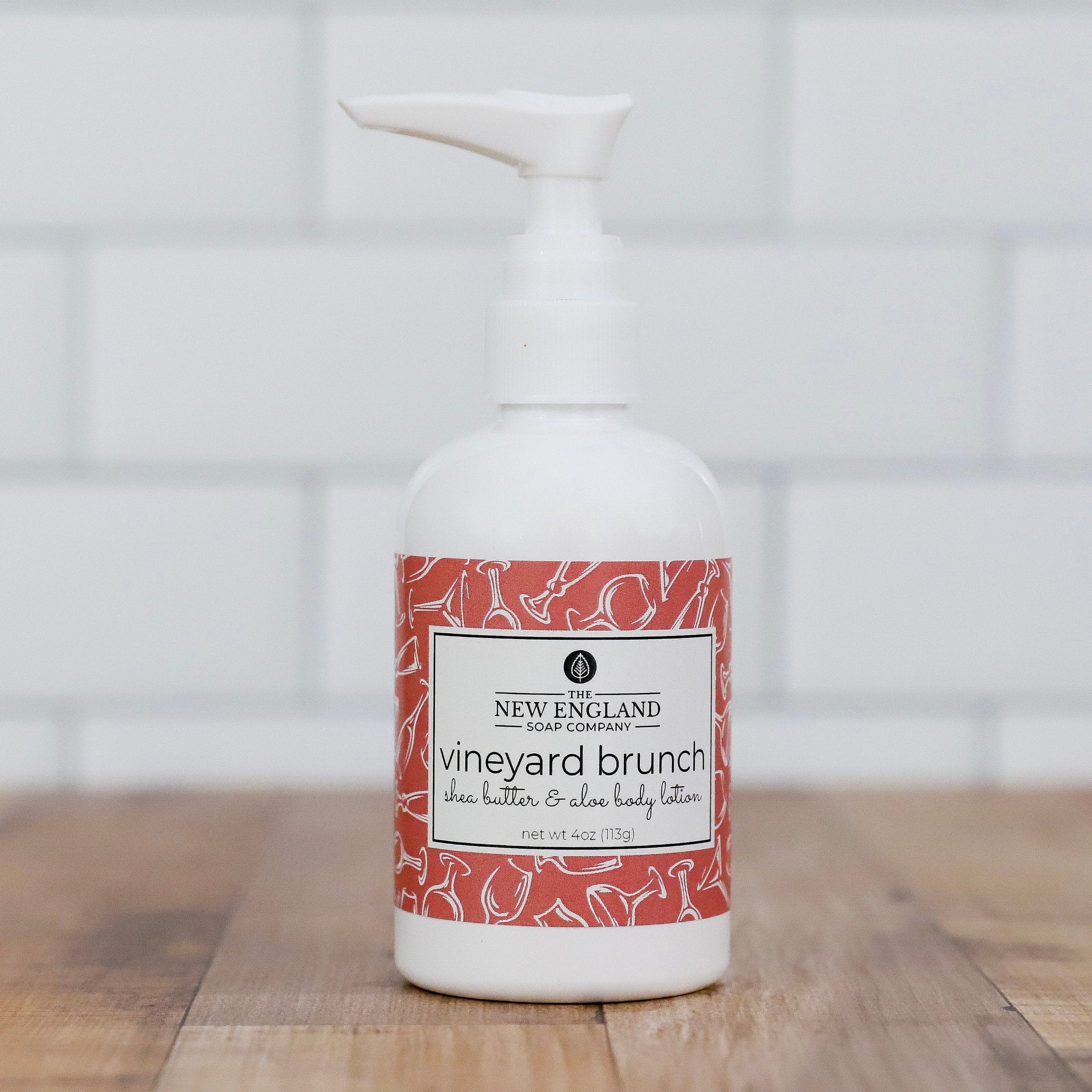 White bottle with a red and white label on a wooden surface Vineyard Brunch Hand and Body Lotion 4 oz