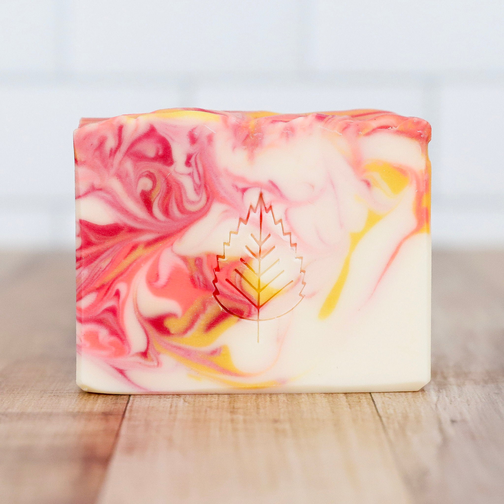 Marbled soap bar with a leaf design on a wooden surface