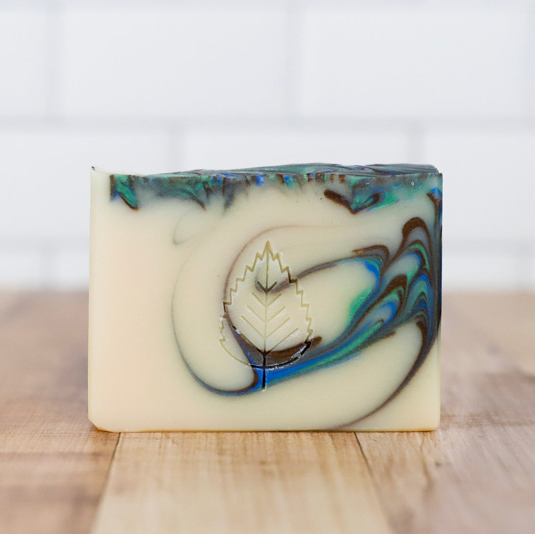 Bar of soap with a leaf design on a wooden surface Dirty Water Artisan Soap