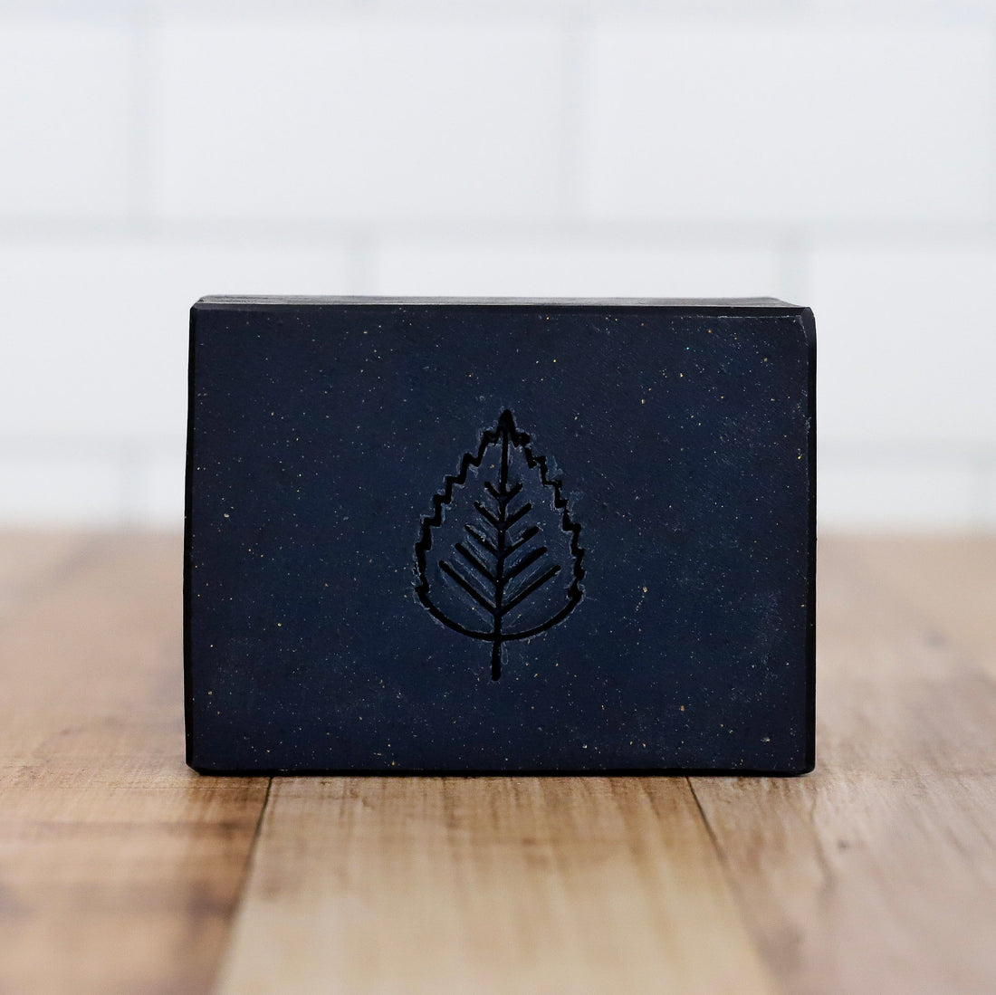 Black soap bar with a leaf design on a wooden surface Midnight Ride Artisan Soap