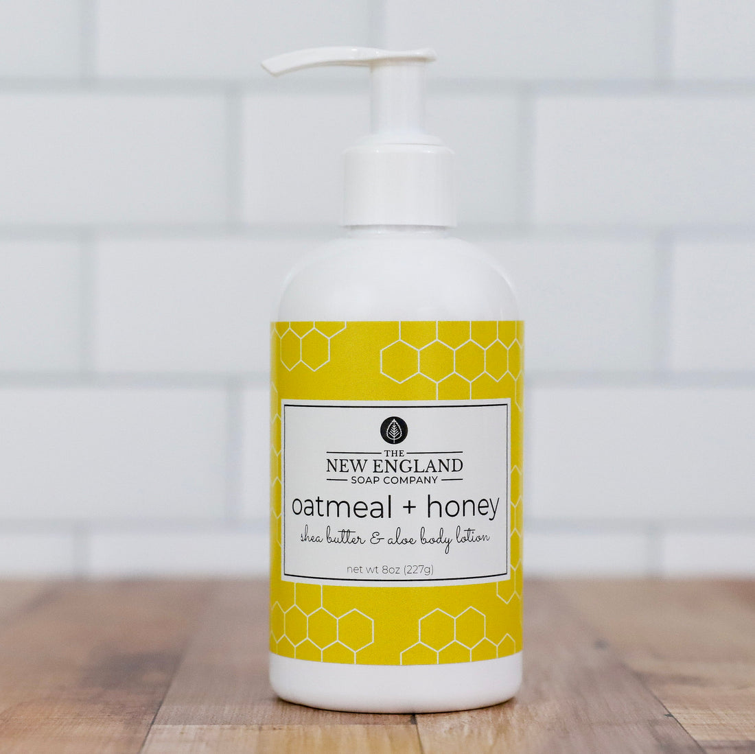 Body lotion bottle with yellow label on a wooden surface and tiled wall background