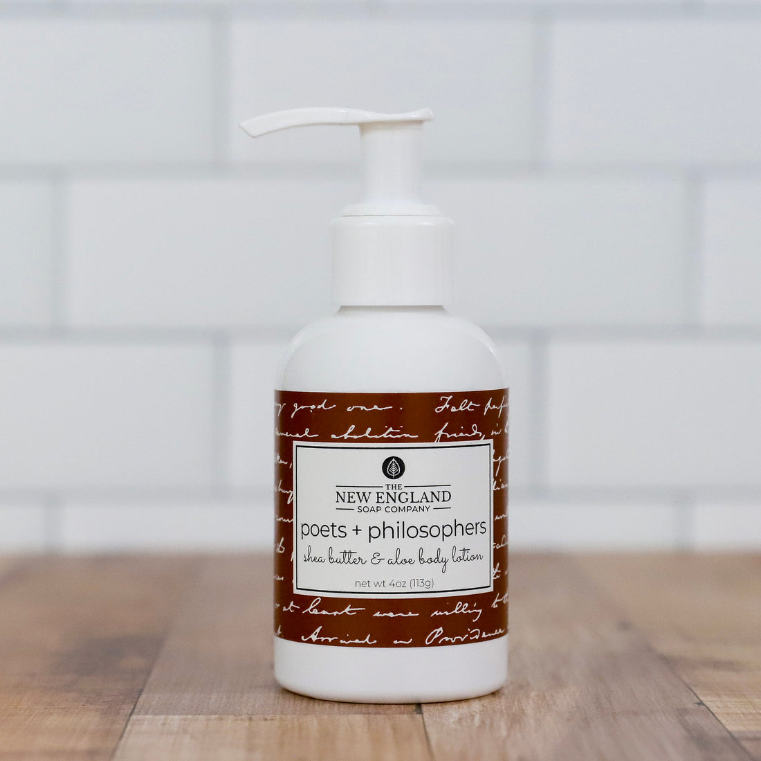 Body lotion bottle with a label on a wooden surface and white background Poets and Philosophers Hand and Body Lotion 4 oz