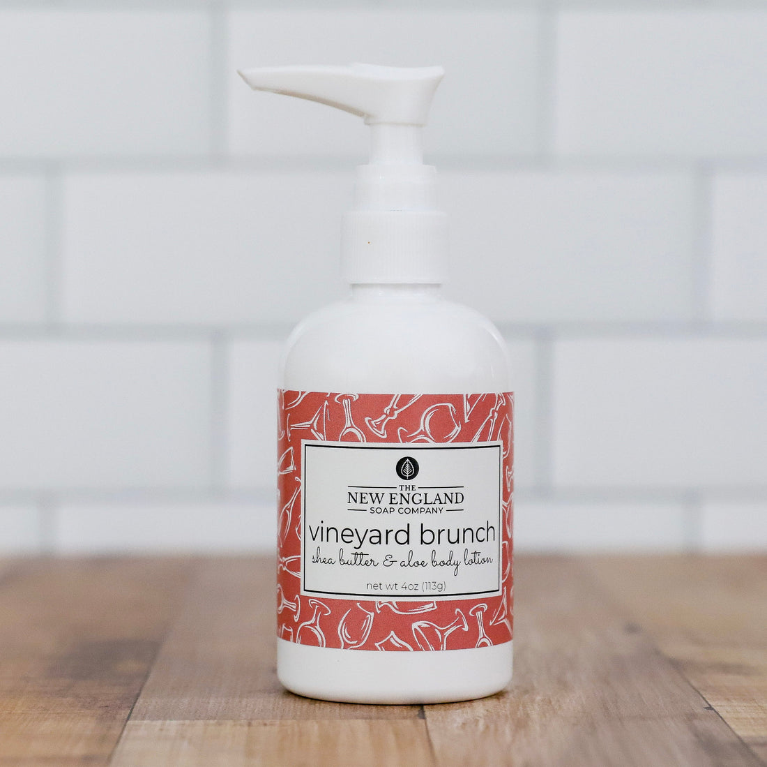 White bottle with a red and white label on a wooden surface Vineyard Brunch Hand and Body Lotion 4 oz