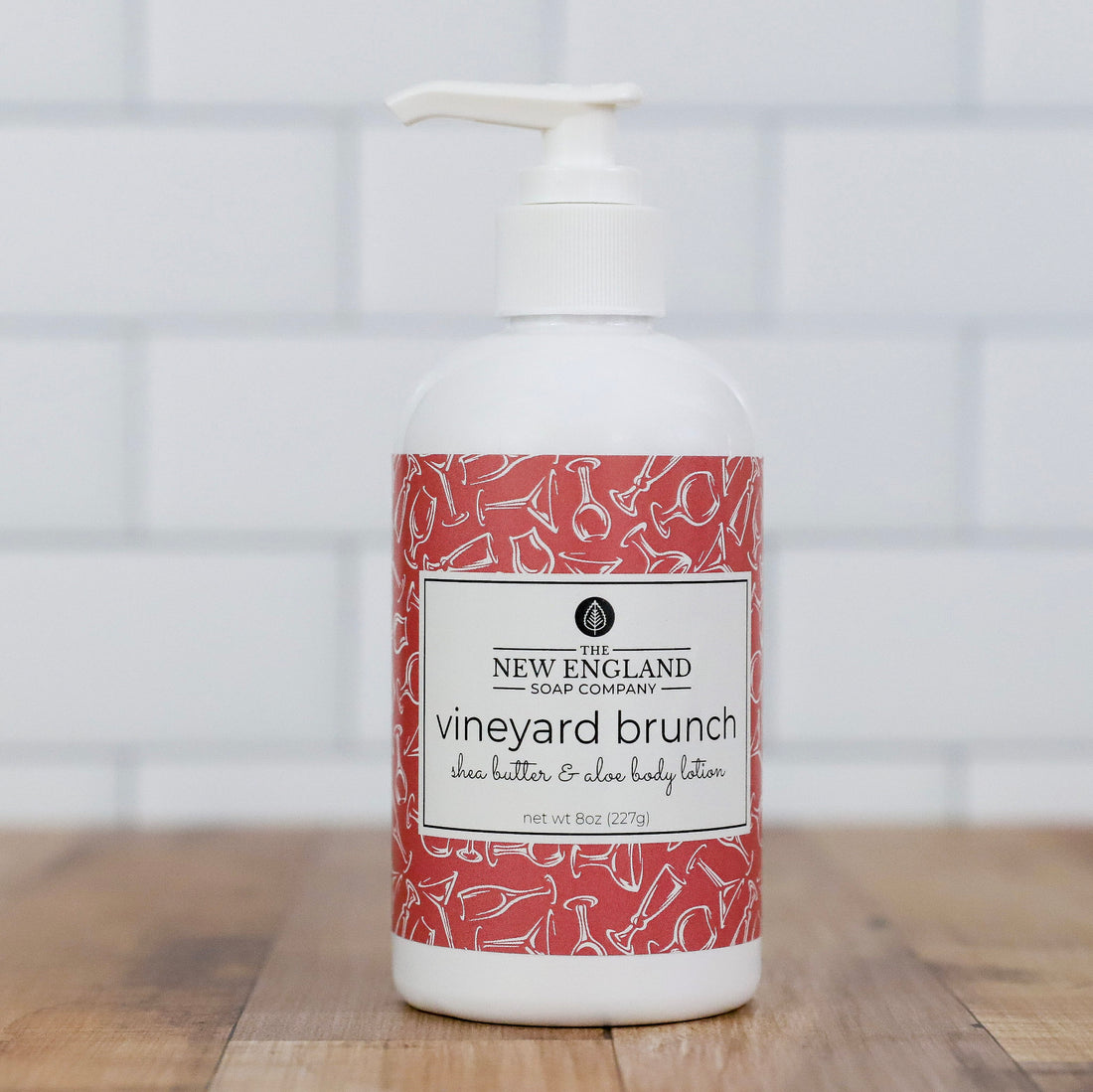 Body lotion bottle with red label on a wooden surface and tiled wall background