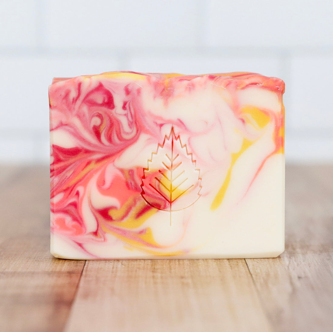 Marbled soap bar with a leaf design on a wooden surface