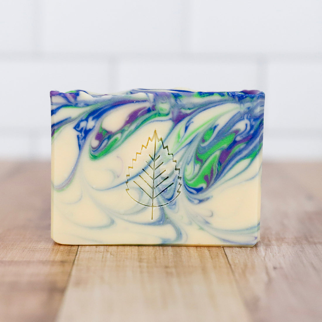 Marbled soap bar with a leaf logo on a wooden surface